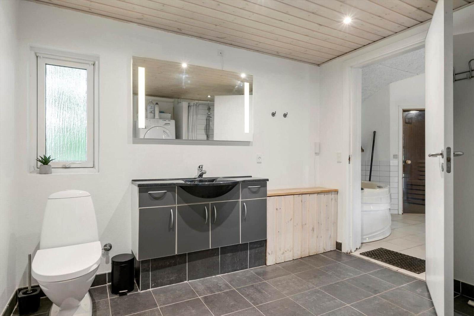 Badezimmer mit Waschbecken, Toilette und Blick in die Badewanne.