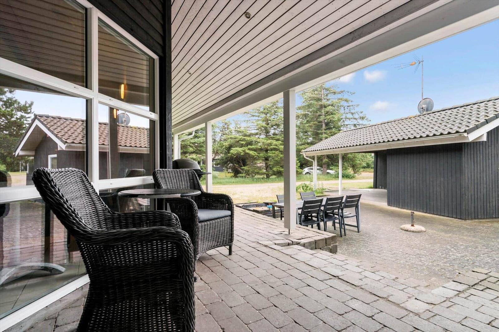 Terrasse mit Sitzgruppe und Grill, Blick auf Garten und Nebengebäude.