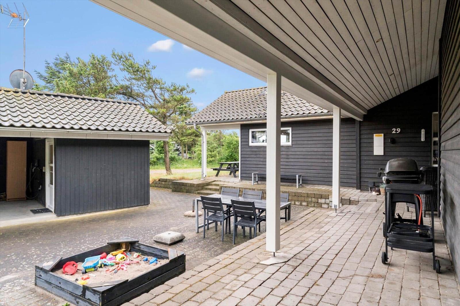 Terrasse mit Grill, Tisch und Stühlen. Sandkasten und Gartenhaus sind vorhanden.