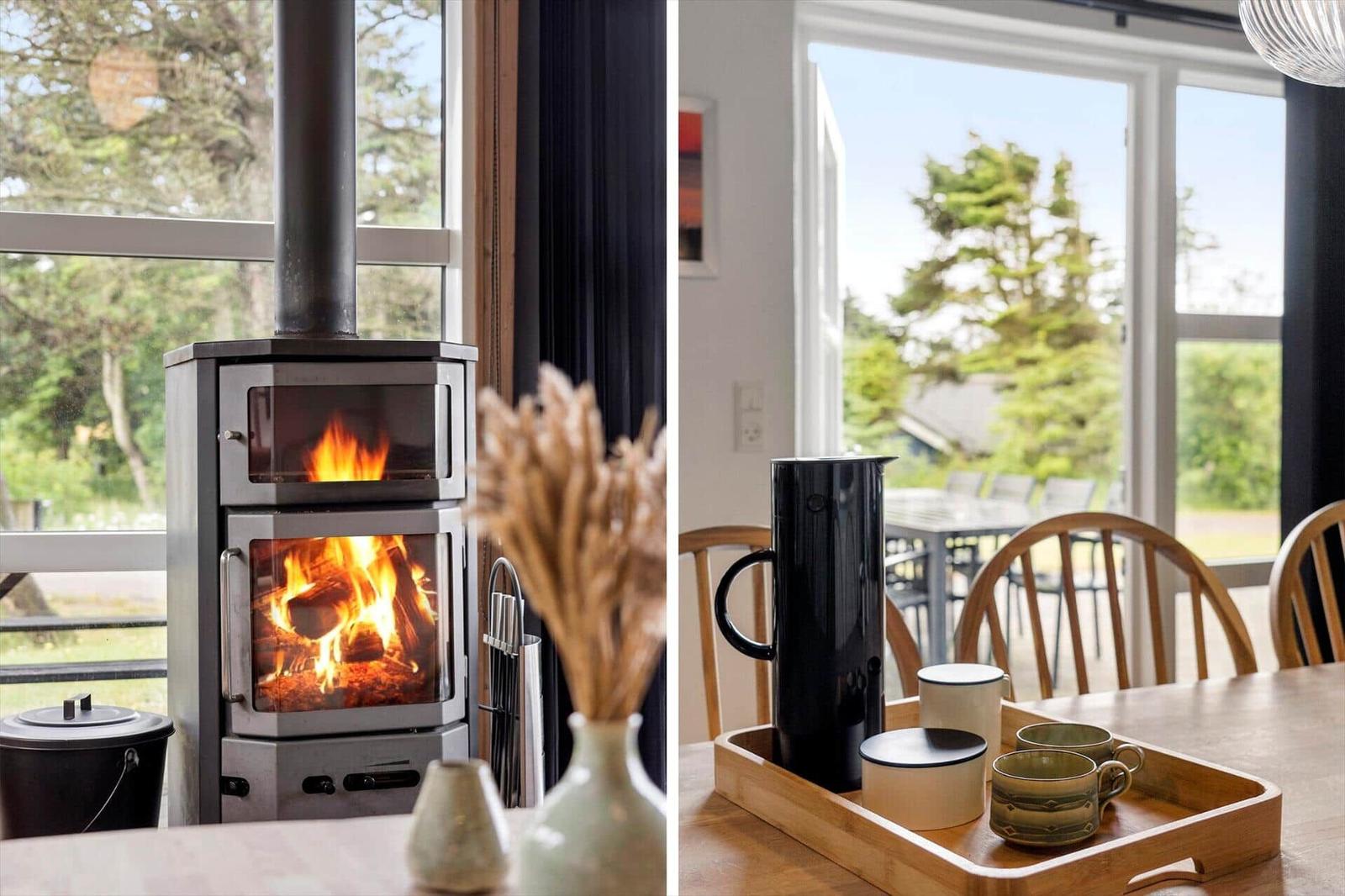 Kaminofen mit brennendem Holz und Blick auf den Garten. Esstisch mit Kaffeetasse und Servierbrett.