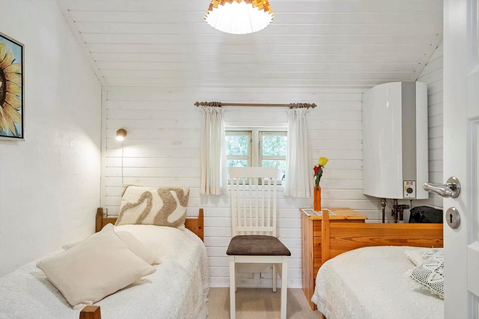 Zimmer mit zwei Betten, Fenster, Stuhl und Heizung.
