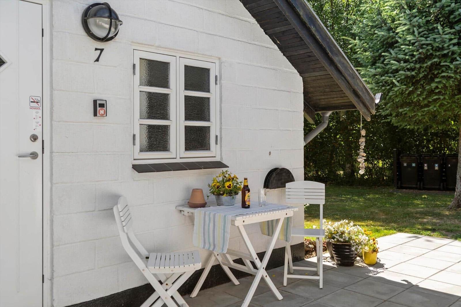 Wohnung mit weißen Wänden, Fenster und Tisch mit Stühlen auf der Terrasse.