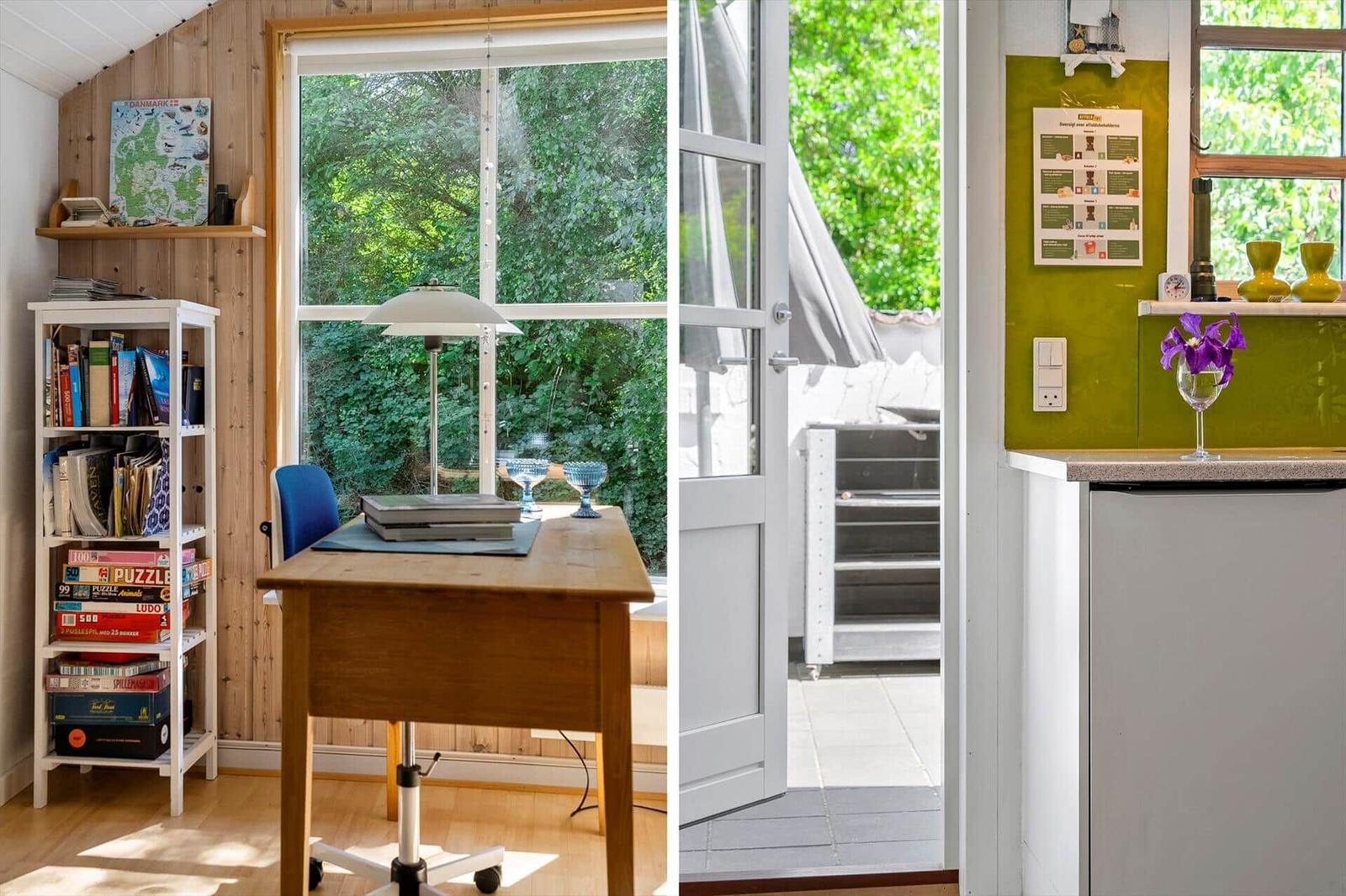 Arbeitszimmer mit Holztisch, Bücherregal und Blick auf grüne Bäume. Durchgang zur Terrasse mit Grillbereich.