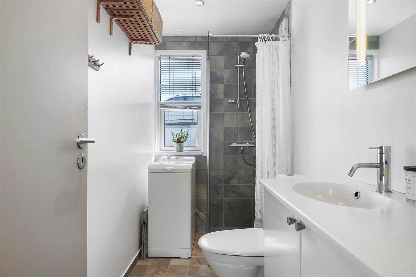 Badezimmer mit Dusche, Waschmaschine und Waschbecken.