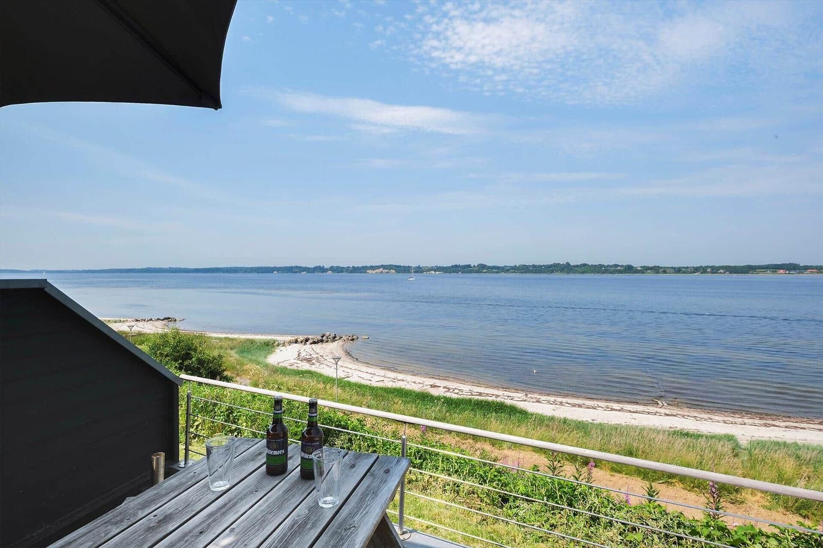 Terrasse mit Tisch und Bierflaschen, Blick auf Strand und See.
