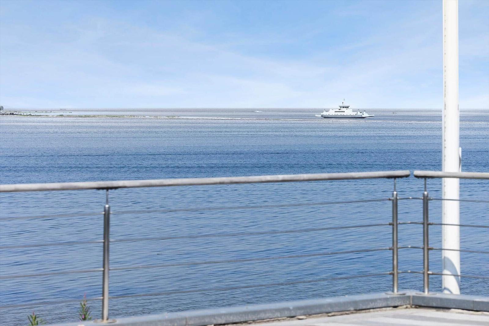 Blick auf das Meer mit einem Schiff in der Ferne und einer Metallbrüstung im Vordergrund.
