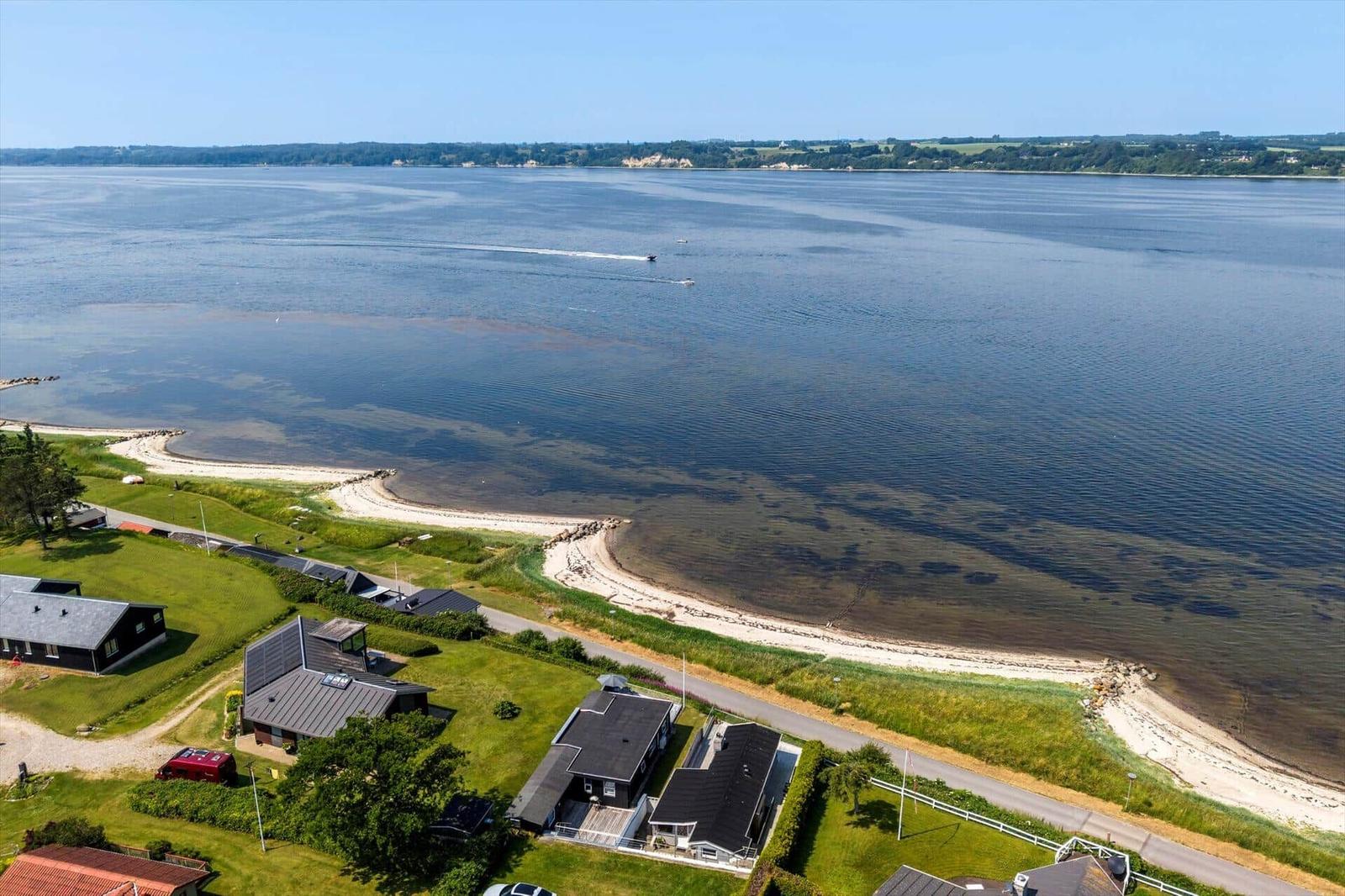 Aerial view of waterfront property with beach, houses, and calm water.