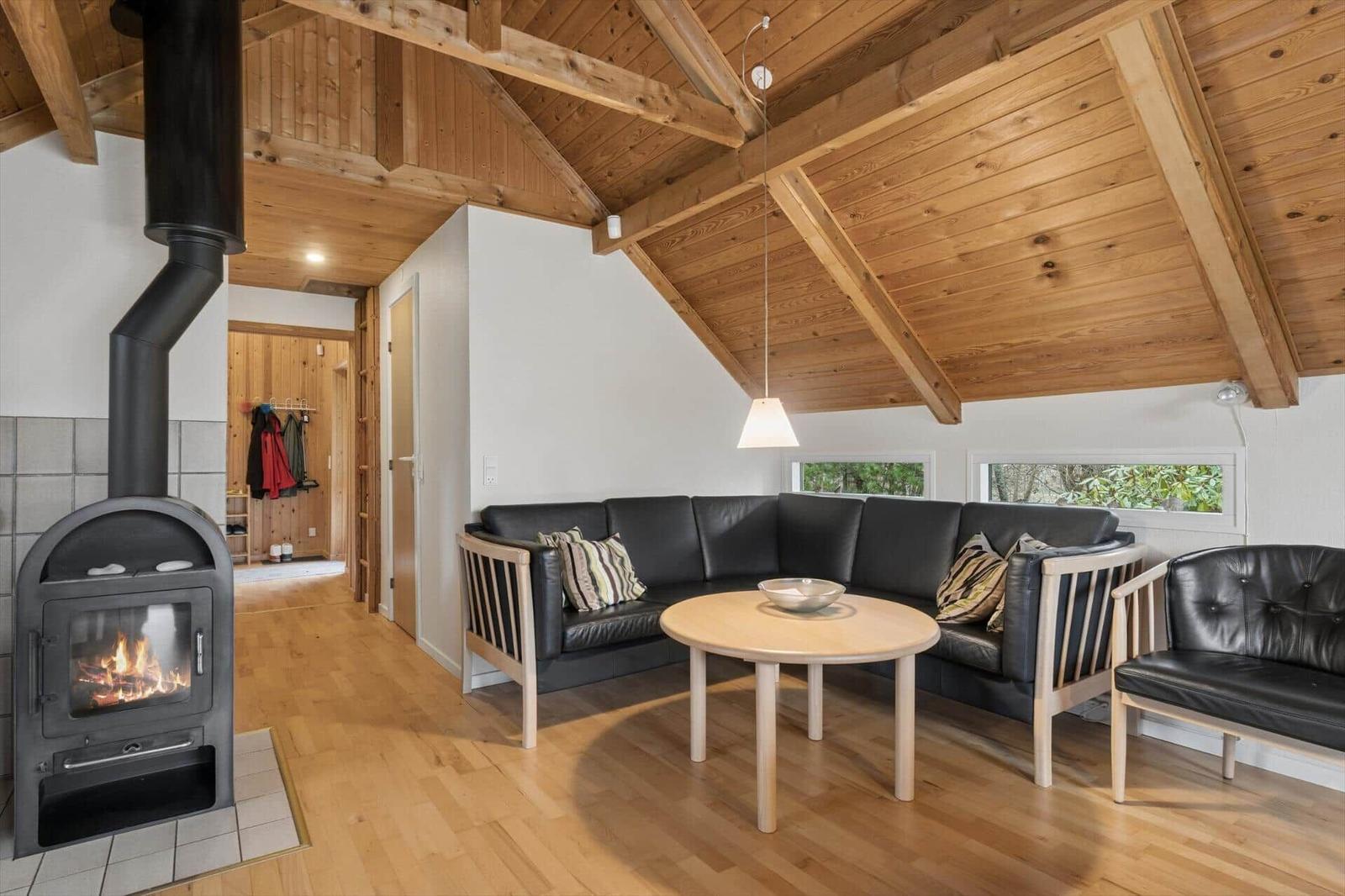 Wohnzimmer mit Holzdecke, Kaminofen, Sofa und Tisch
