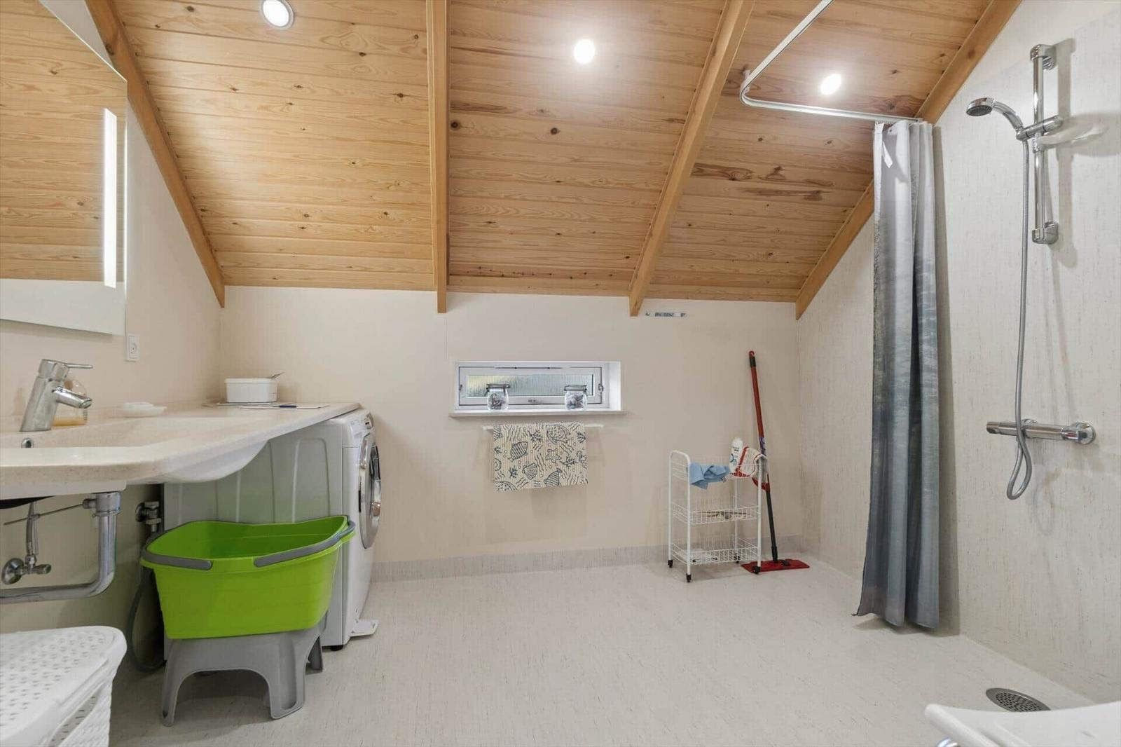 Badezimmer mit Dusche, Waschmaschine und Fenster