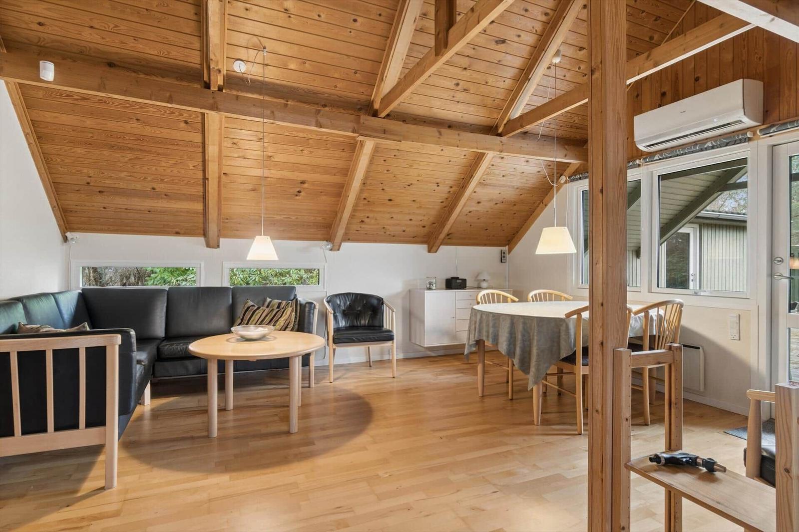 Wohn- und Essbereich mit Holzdecke, Sofa, Tisch und Stühlen.