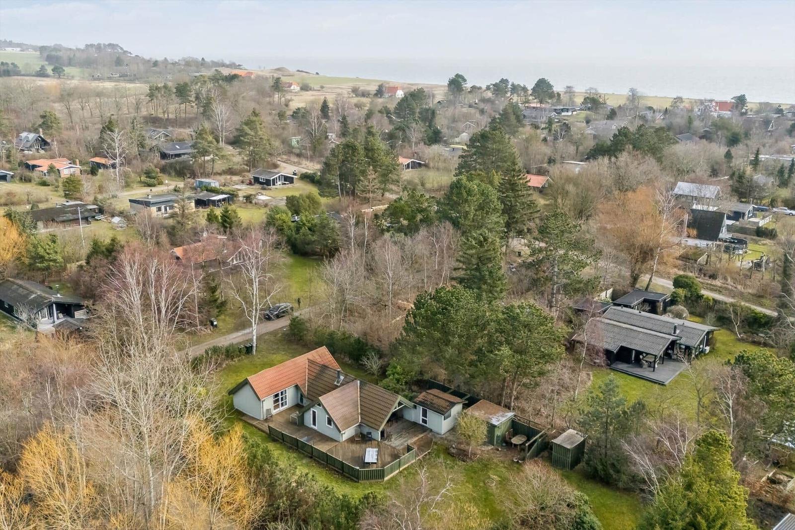 Haus mit Terrasse und Garten in ländlicher Umgebung mit Bäumen und Blick auf die Küste.