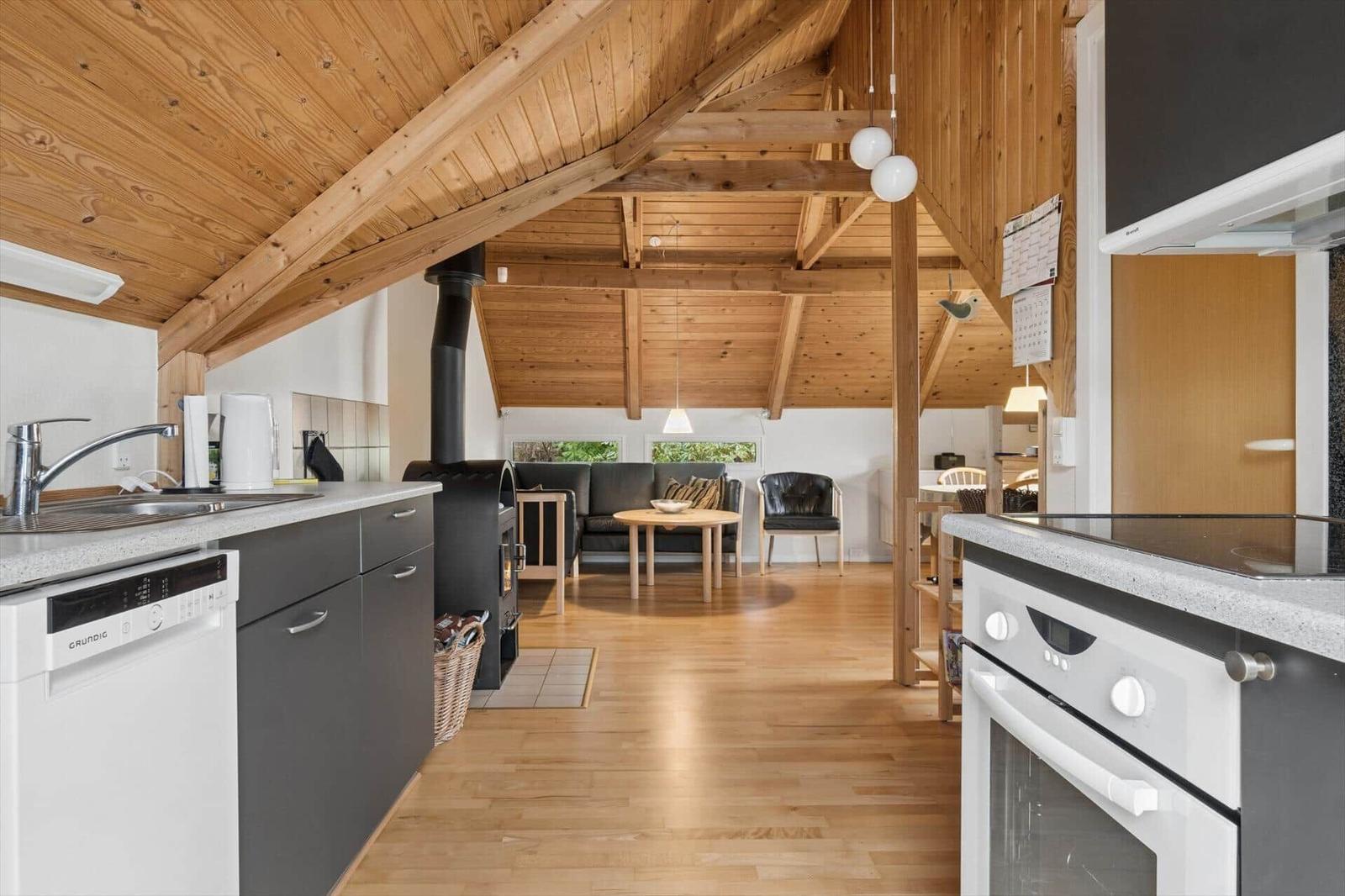 Küche mit Holzdecke, Esstisch und Sofa im Hintergrund.