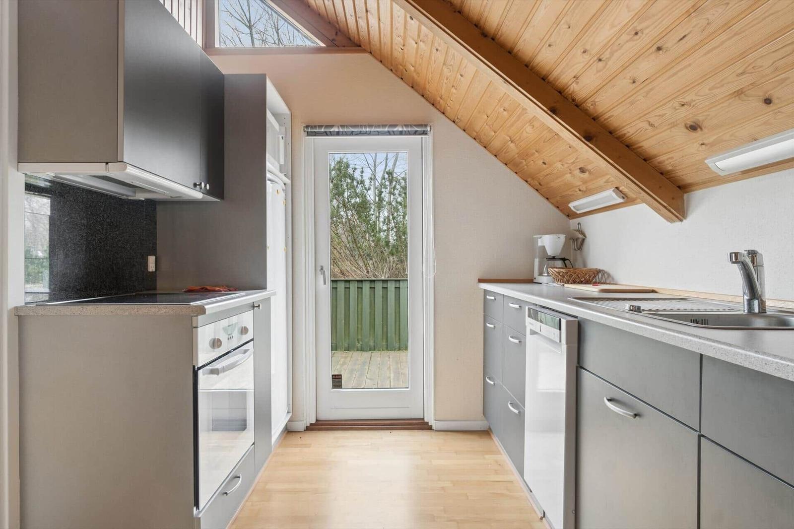 Küche mit Holzdecke, Fenster und Tür zum Balkon.