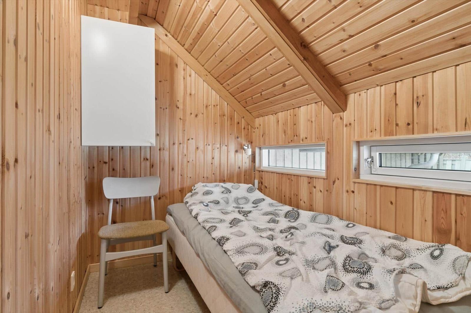Ein Schlafzimmer mit Holzwänden, einem Bett und einem Stuhl.