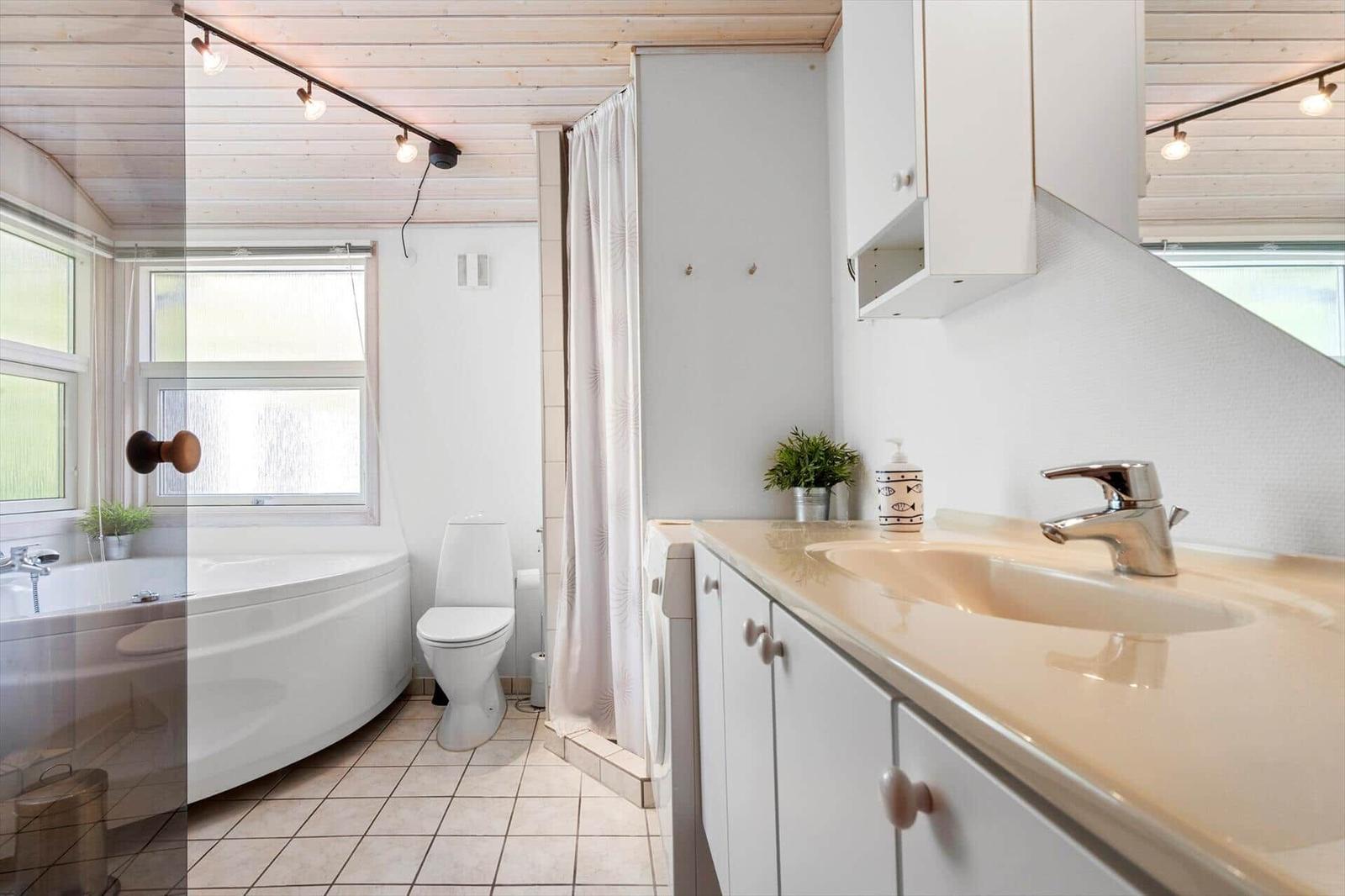 Badezimmer mit Badewanne, Toilette und Waschbecken mit Spiegel.