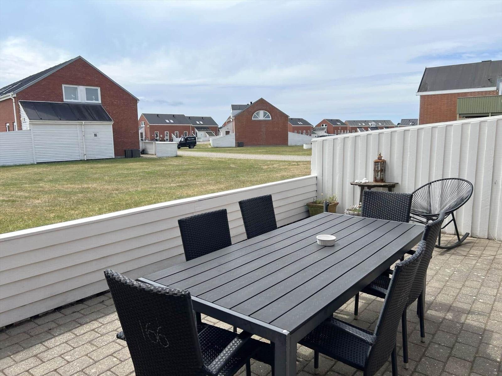 Terrasse mit Tisch und Stühlen, Blick auf Grünfläche und Häuser.