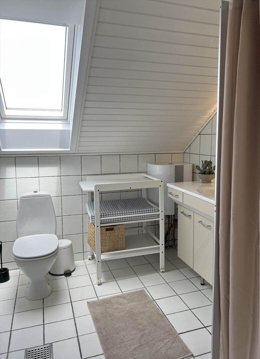 Badezimmer mit Toilette, Waschbecken und Wickeltisch unter Dachschrägen.