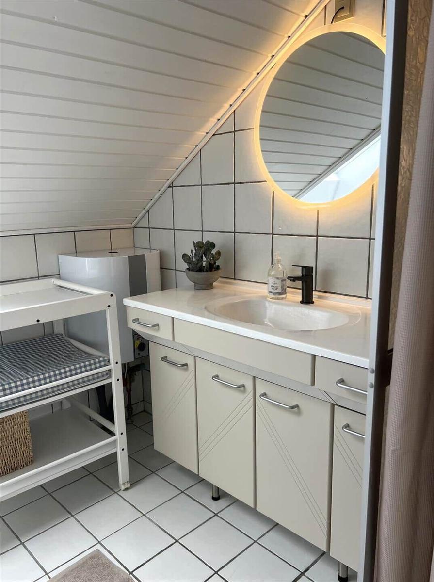 Badezimmer mit Waschbecken, Spiegel und Babywanne unter Dachschräge.
