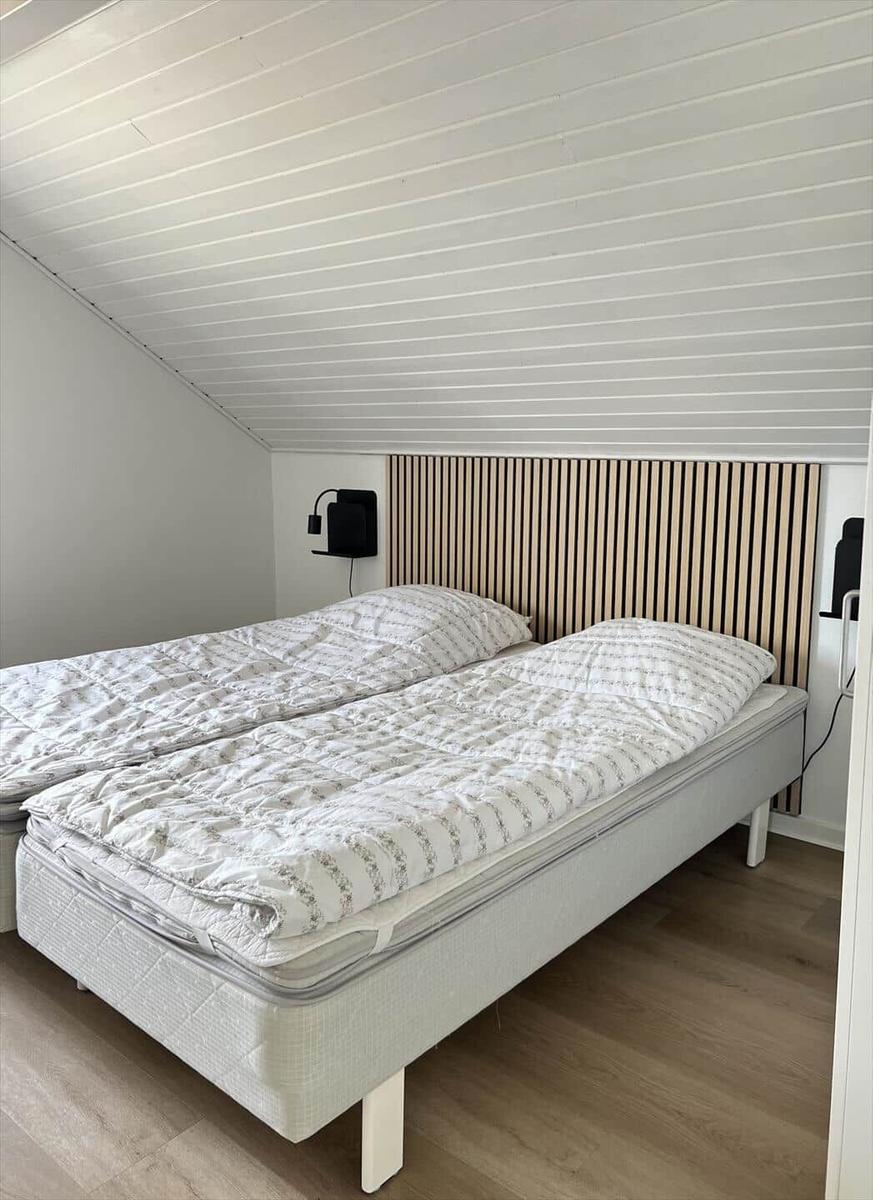 Schlafzimmer mit Doppelbett, Holzpaneelen und schrägem Dach