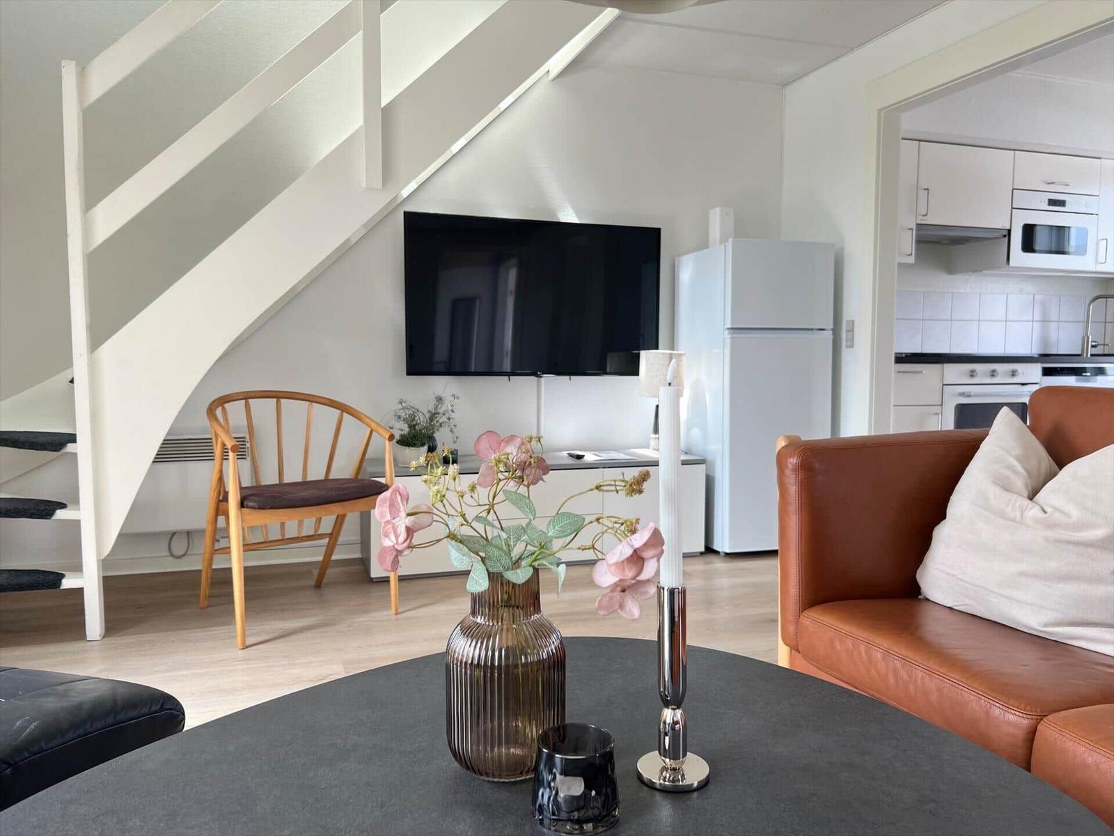 Wohnzimmer mit Sofa, Fernseher und Küchenbereich im Hintergrund.