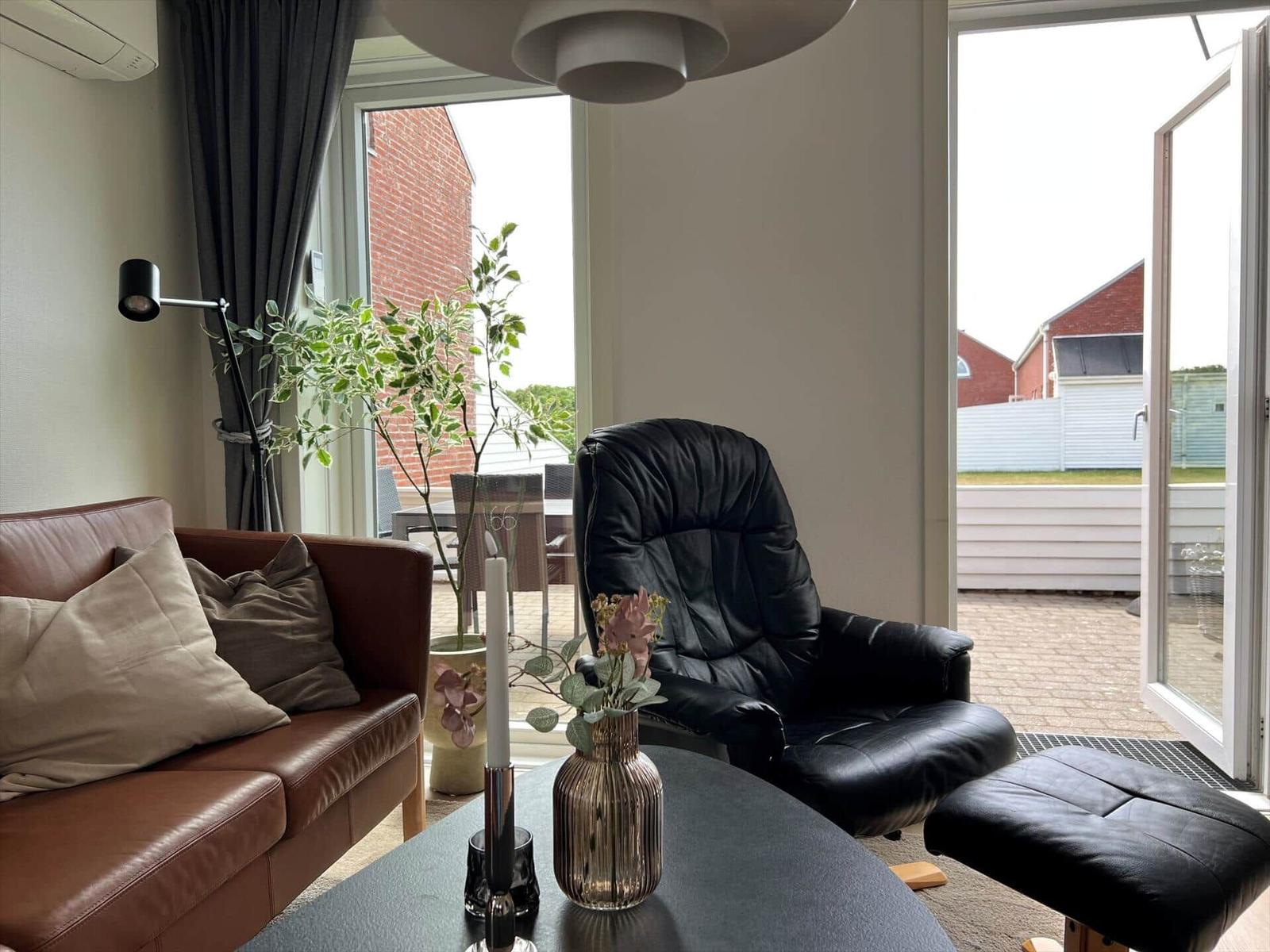 Ein Wohnzimmer mit braunem Sofa, schwarzer Ledersessel und Tisch mit Vasen.