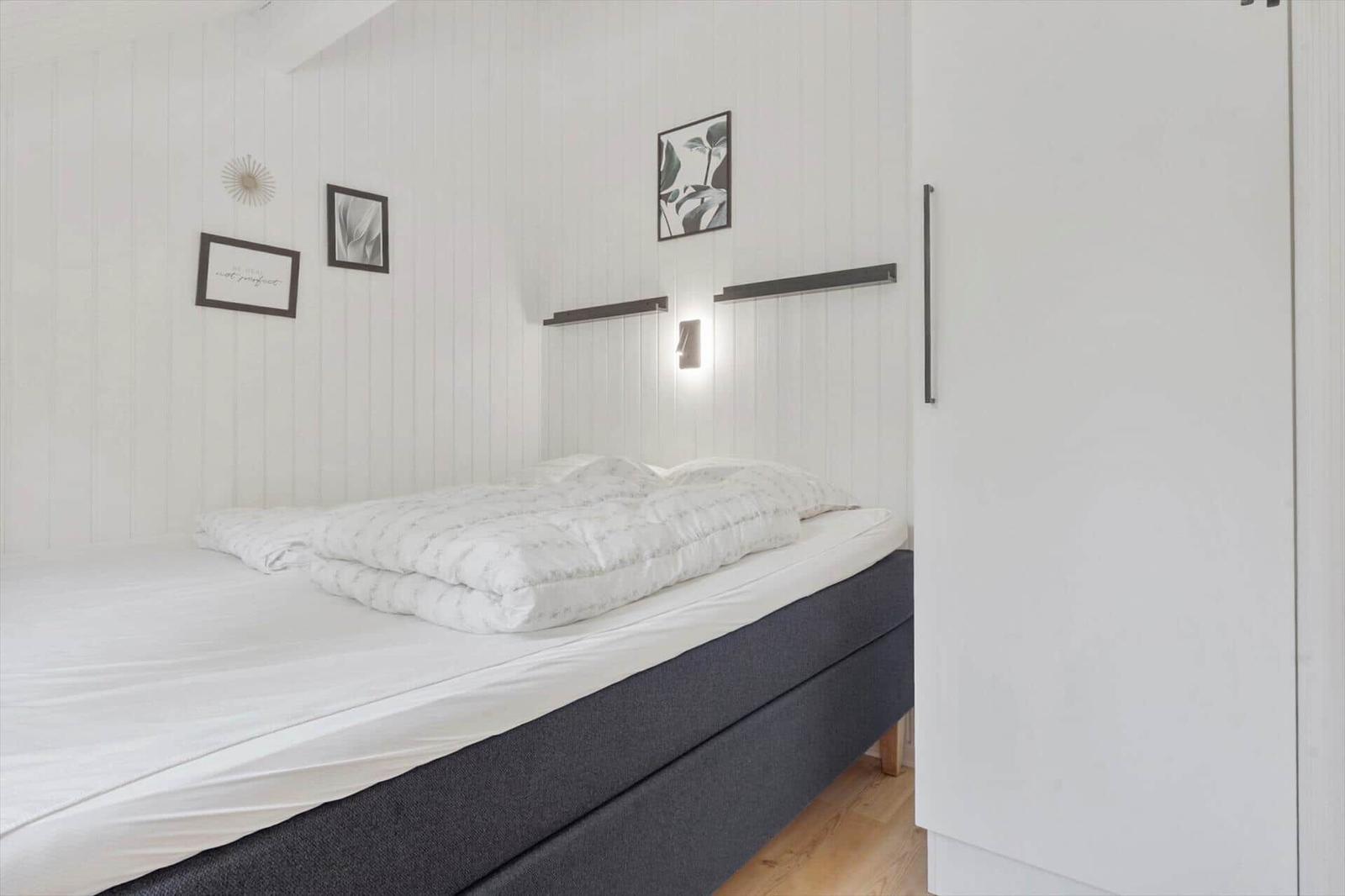 Schlafzimmer mit Bett, Wandbildern und Kleiderschrank.