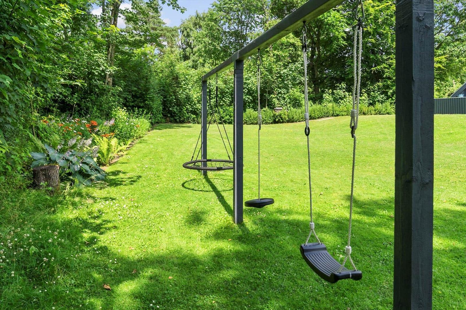 Schaukelanlage im Garten mit Grasfläche und Blumenbeete
