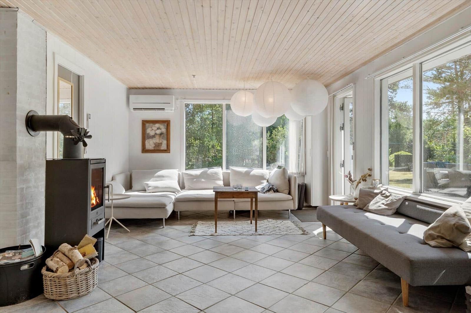 Wohnzimmer mit Holzdecke, Kamin und großen Fenstern. Sofa, Couch und Tisch.