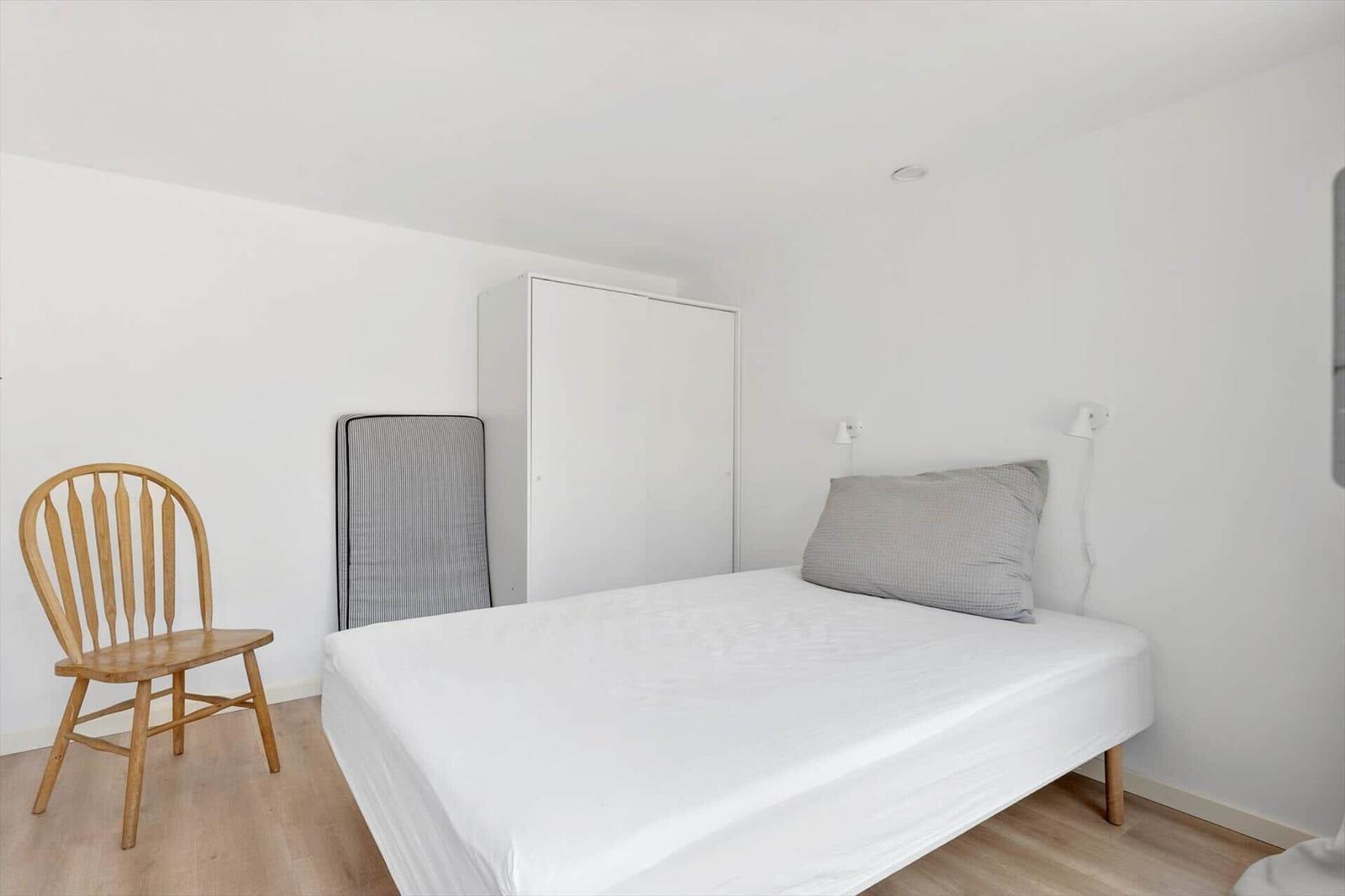 Schlafzimmer mit Bett, Kleiderschrank und Holzstuhl.