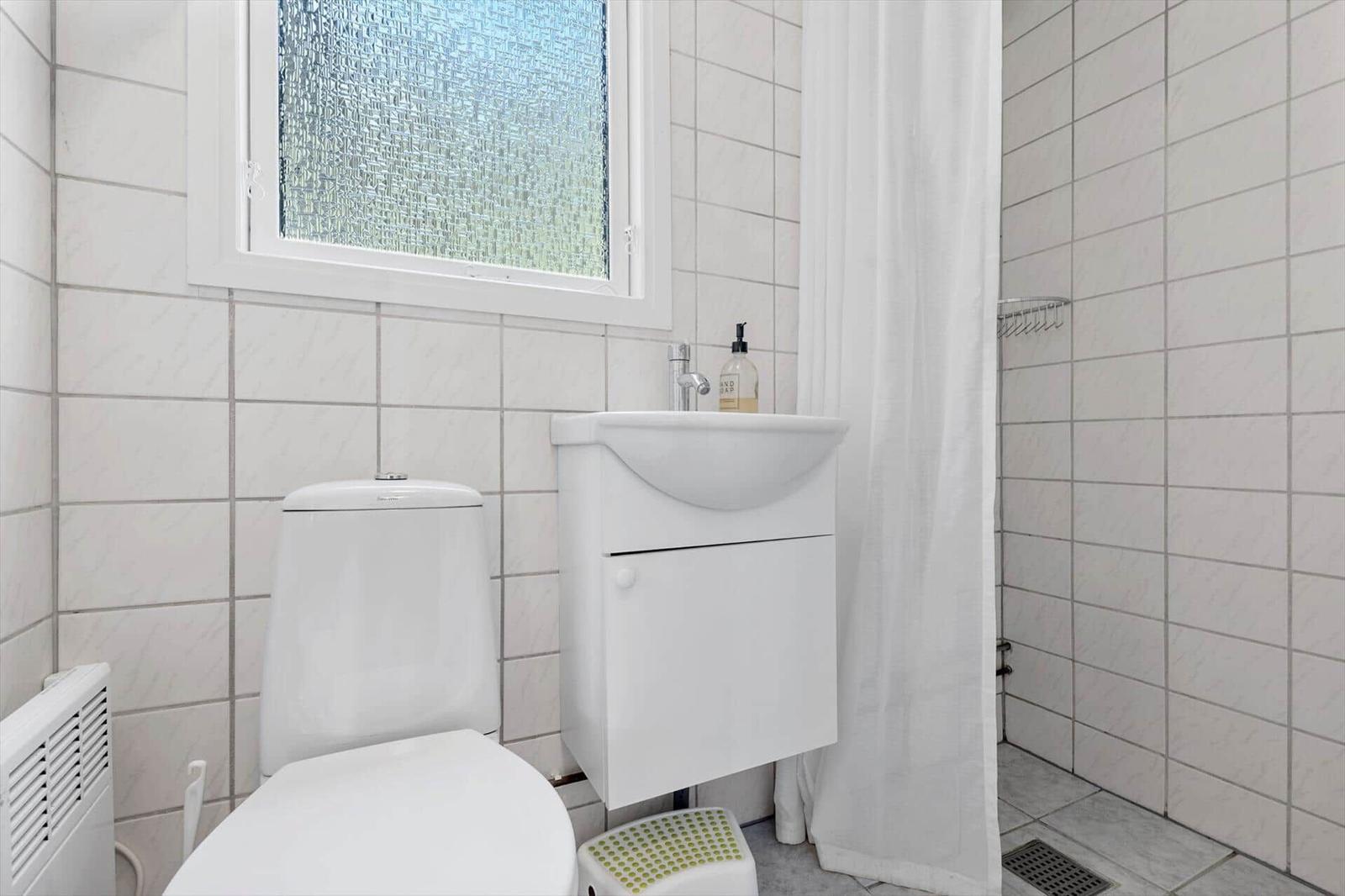 Badezimmer mit Toilette, Waschbecken und Dusche mit Duschvorhang.