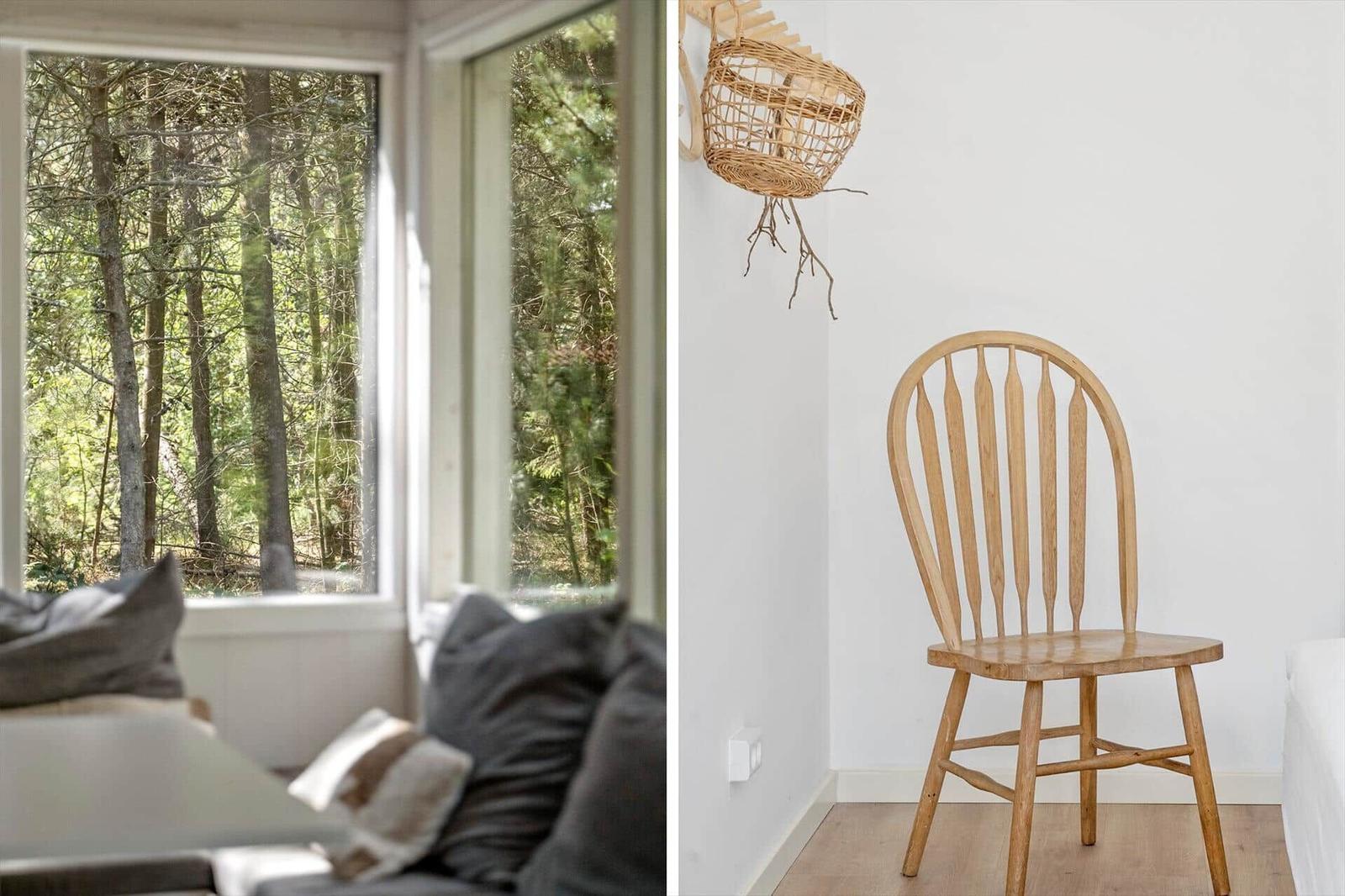 Ein Wohnzimmer mit Blick auf einen Wald und ein Holzstuhl in einem Raum mit weißer Wand.