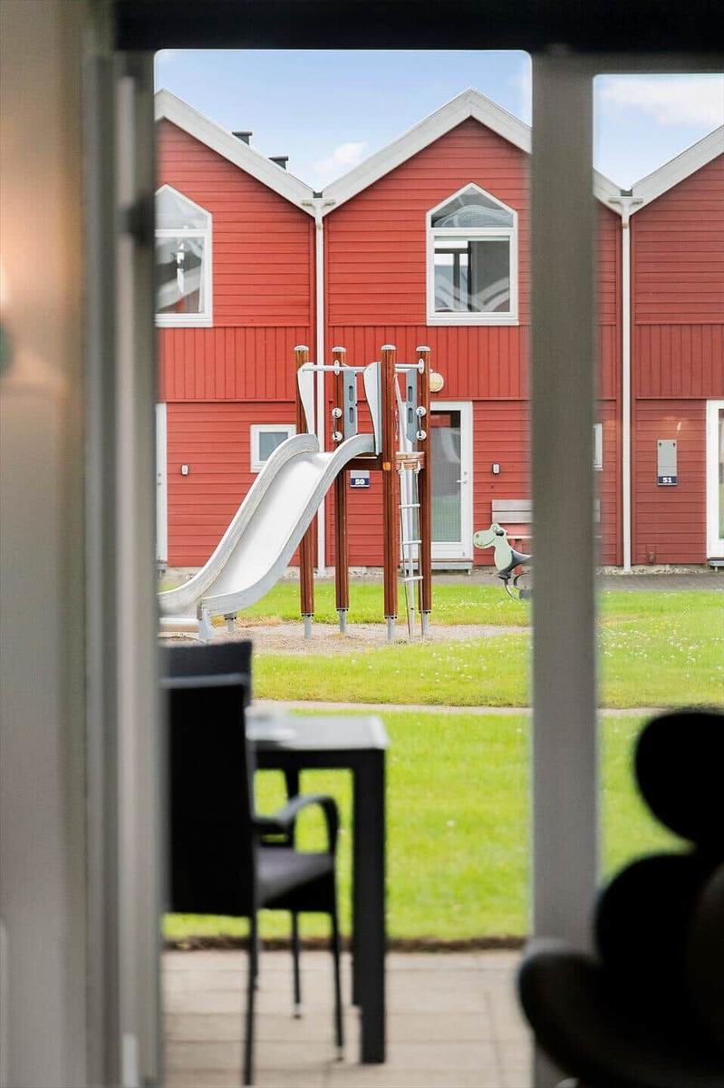 Von der Terrasse aus sieht man einen Spielplatz mit Rutsche vor roten Häusern.