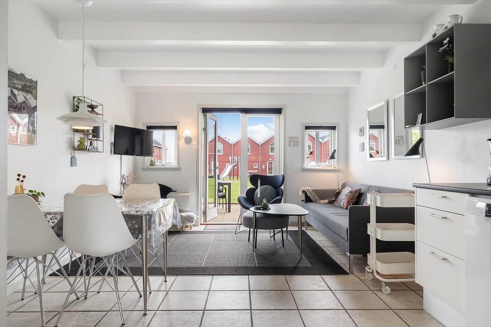 Wohn- und Essbereich mit Terrasse, Sofa, Esstisch und Küchenzeile.