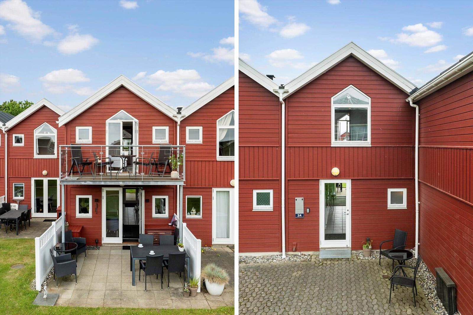 Rotes Ferienhaus mit Balkon und Terrasse. Außenbereich mit Gartenmöbeln und Pflanzen.