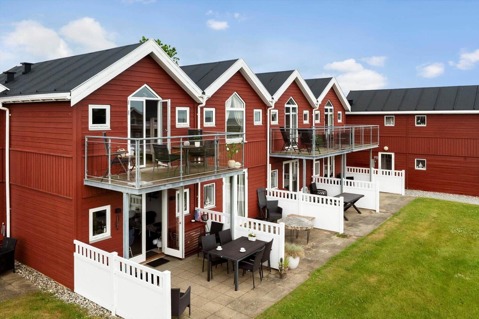 Rote Holzhäuser mit Balkonen und Terrassen im Freien.