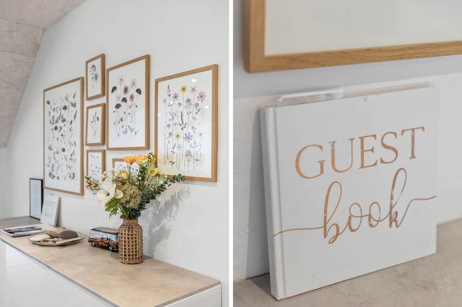 Wand mit Blumenbildern und Gästebuch auf Konsole