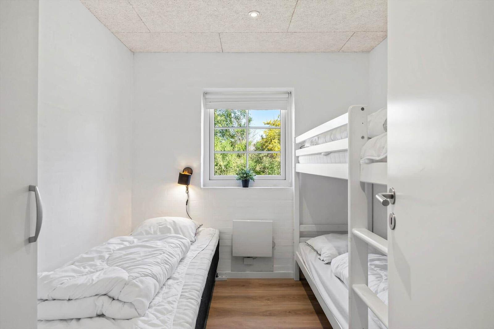 Zimmer mit Etagenbett und Einzelbett, Fenster mit Blick auf Grün.