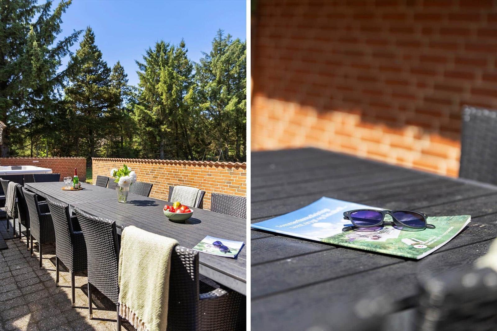 Terrasse mit Tisch, Stühlen und Blick auf Wald. Sonnenbrille und Broschüre auf Tisch.
