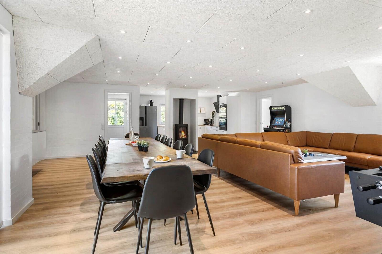 Großes Wohn- und Esszimmer mit braunem Sofa, Esstisch und Kamin.