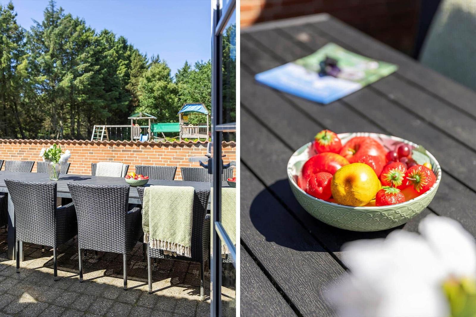 Terrasse mit Tisch und Stühlen, Obstschale und Spielplatz im Hintergrund.
