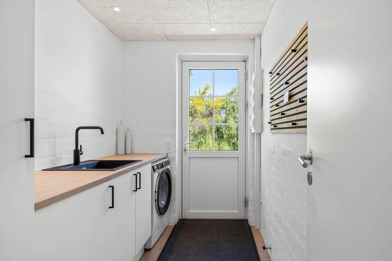 Wohnung mit Waschmaschine, Spüle und Tür zum Garten.