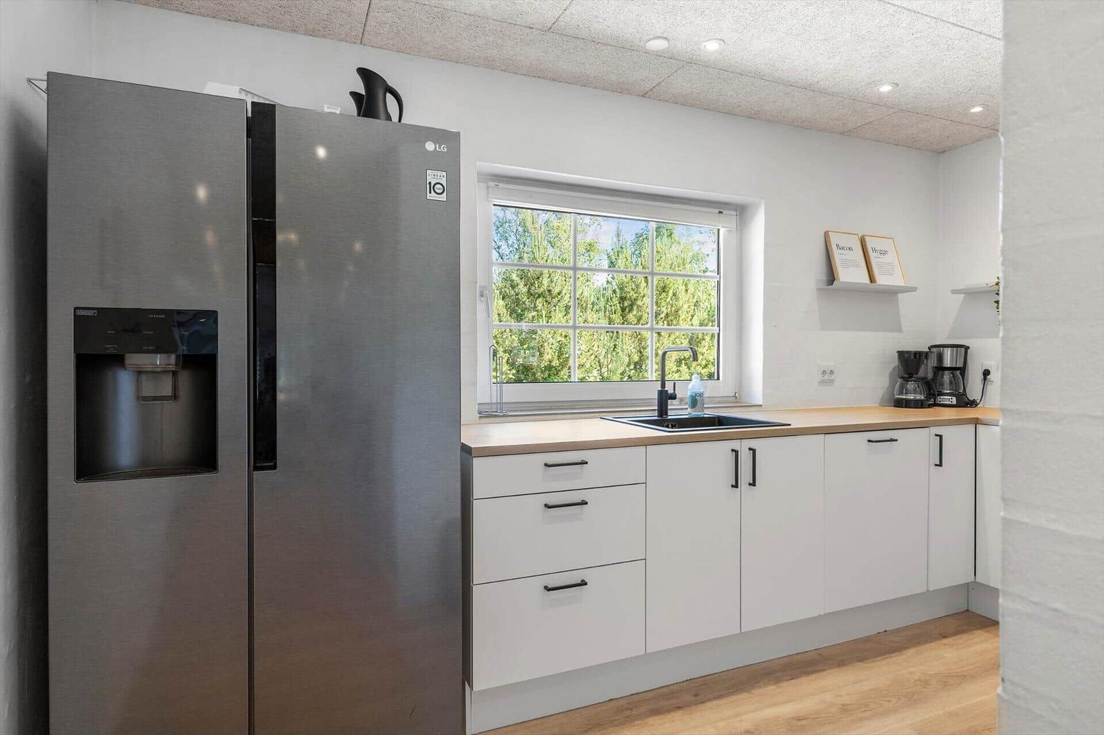 Moderne Küche mit Kühlschrank, Arbeitsplatte und Fenster.