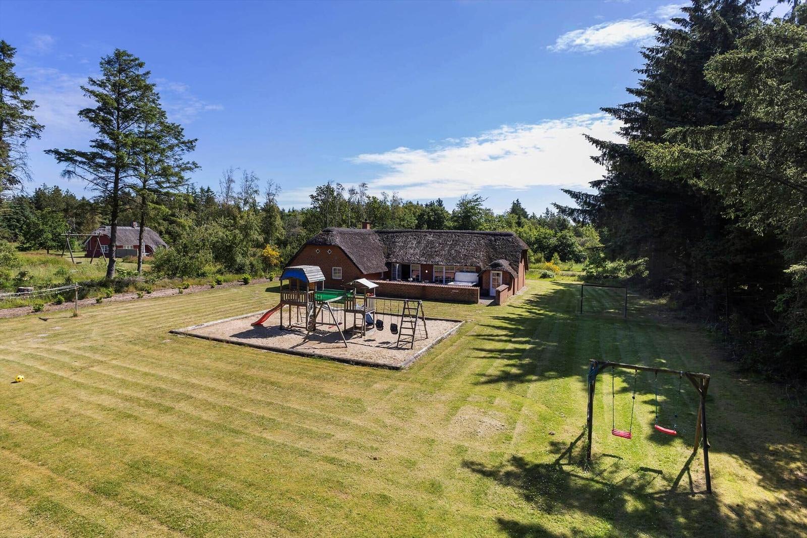Haus mit Spielplatz und Schaukel auf grünem Grundstück.