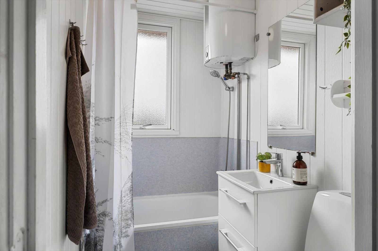 Badezimmer mit Dusche, Waschbecken und Spiegel. Wandfarbe weiß und grau.