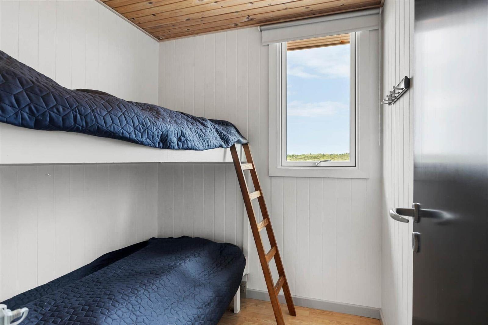 Zimmer mit Doppelstockbett, Holzdecke und Fenster mit Blick auf Grünflächen.