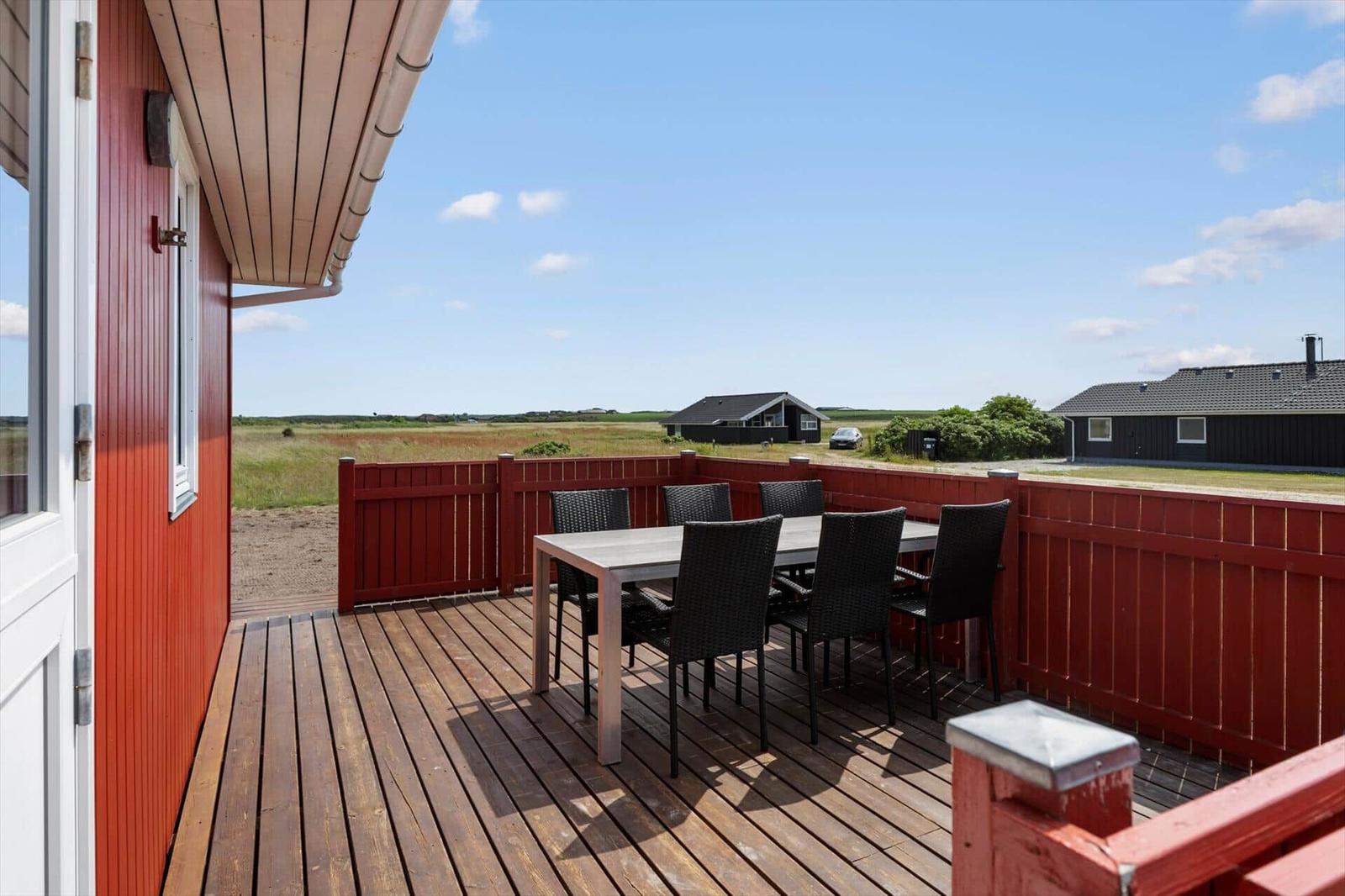 Terrasse mit Tisch und Stühlen, Blick auf Felder und Häuser.
