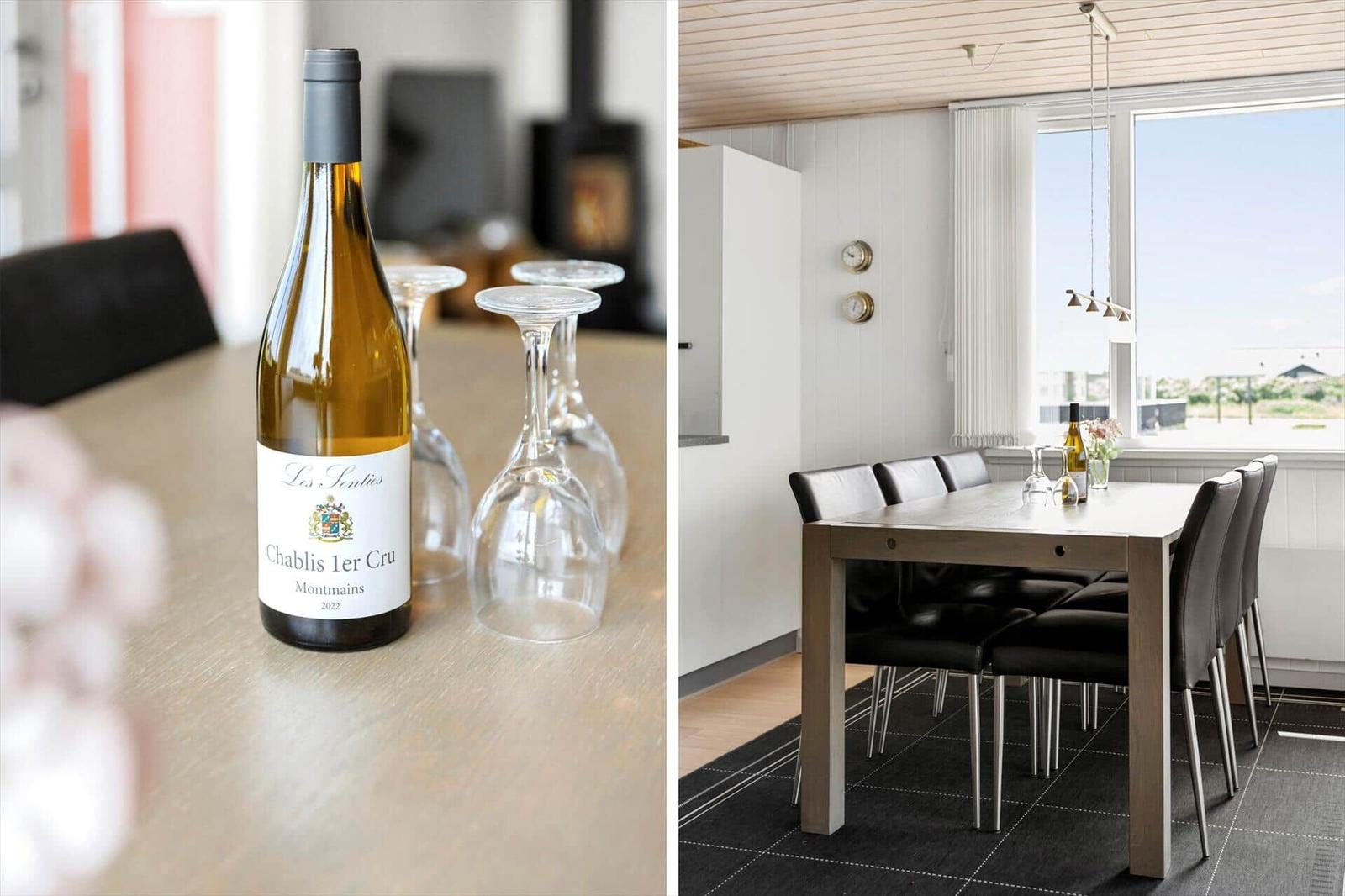 Esszimmer mit Tisch, Stühlen und Blick aus dem Fenster. Flasche Weißwein und Gläser auf Tisch.