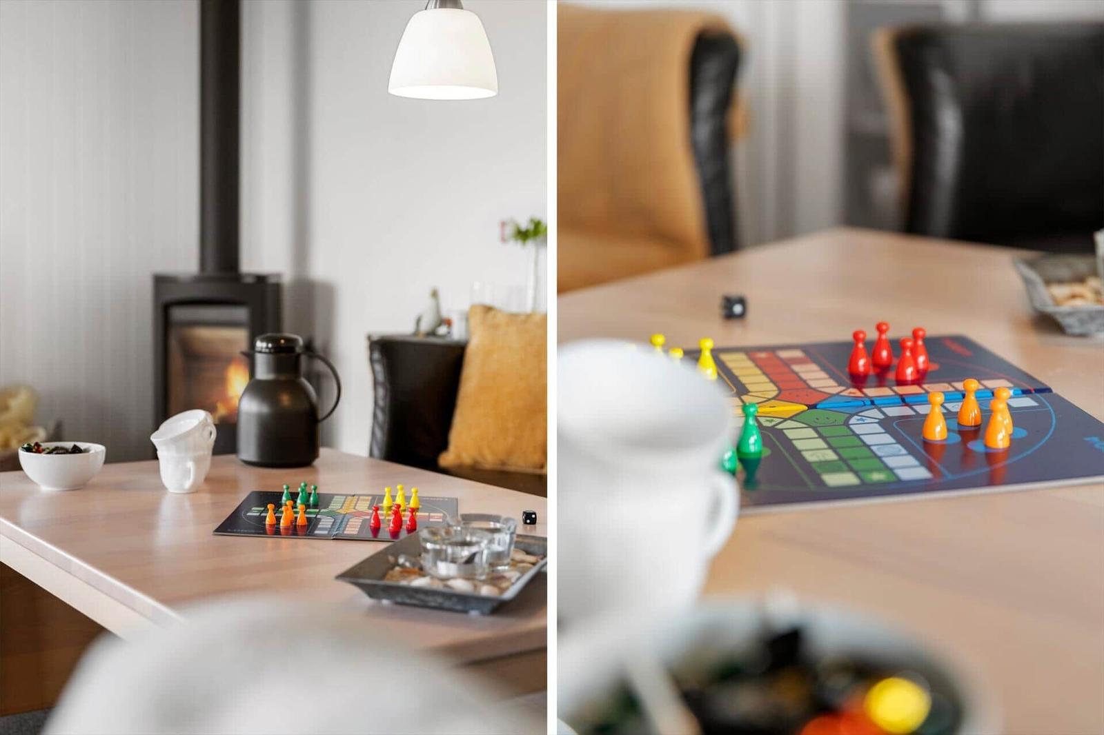 Tisch mit Spielbrett und Spielsteinen, Kamin und Beleuchtung im Hintergrund.