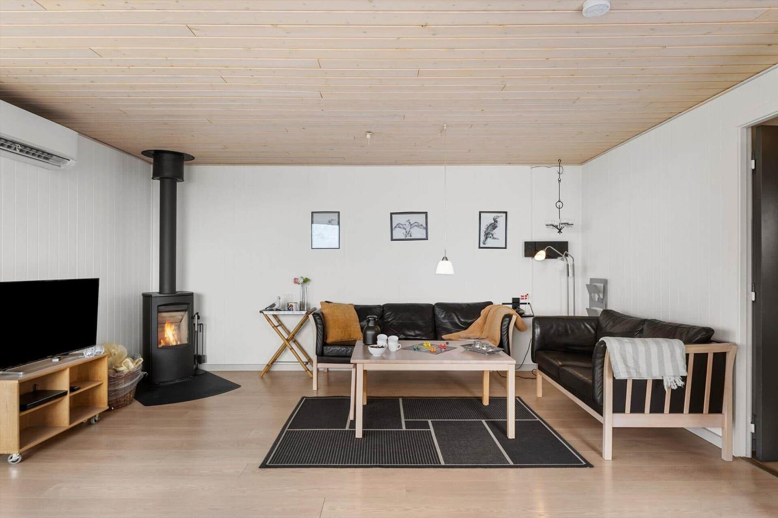 Wohnzimmer mit Kamin, Sofa, Tisch und Fernseher.