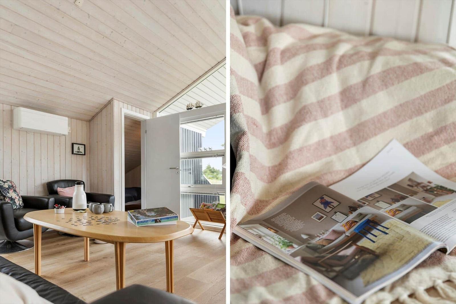 Wohnzimmer mit Holzdecke und Tisch. Bett mit gestreifter Decke und offenem Buch.